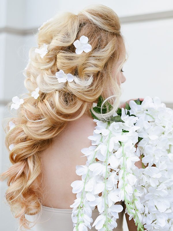 Capelli raccolti ed intrecciati biondi con petali di margherita, idea per sposa