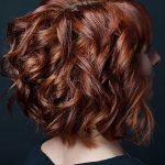 Capelli ondulati di lunghezza media e colore rosso, con mullet frontale